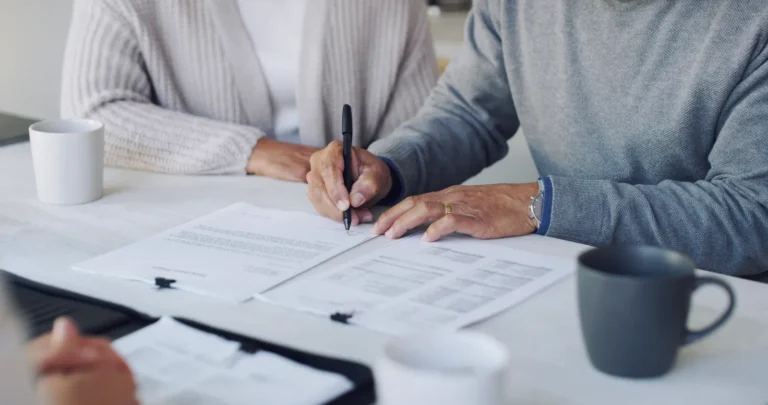 Twee personen bespreken en ondertekenen documenten aan tafel