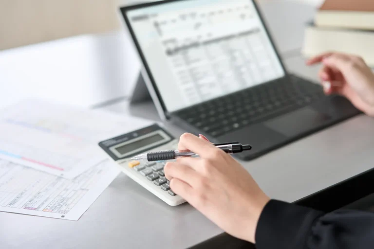 Woman processes financial data with a laptop and calculator