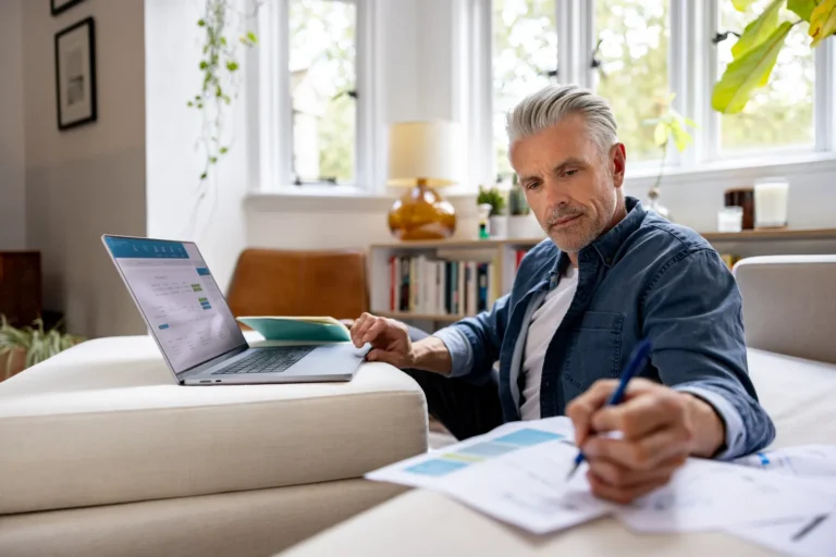 Man controleert rekeningen achter zijn laptop aan de keukentafel