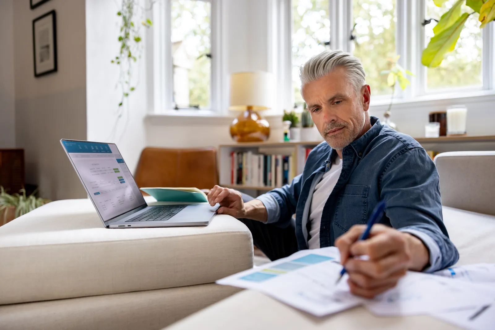 Man controleert rekeningen achter zijn laptop aan de keukentafel